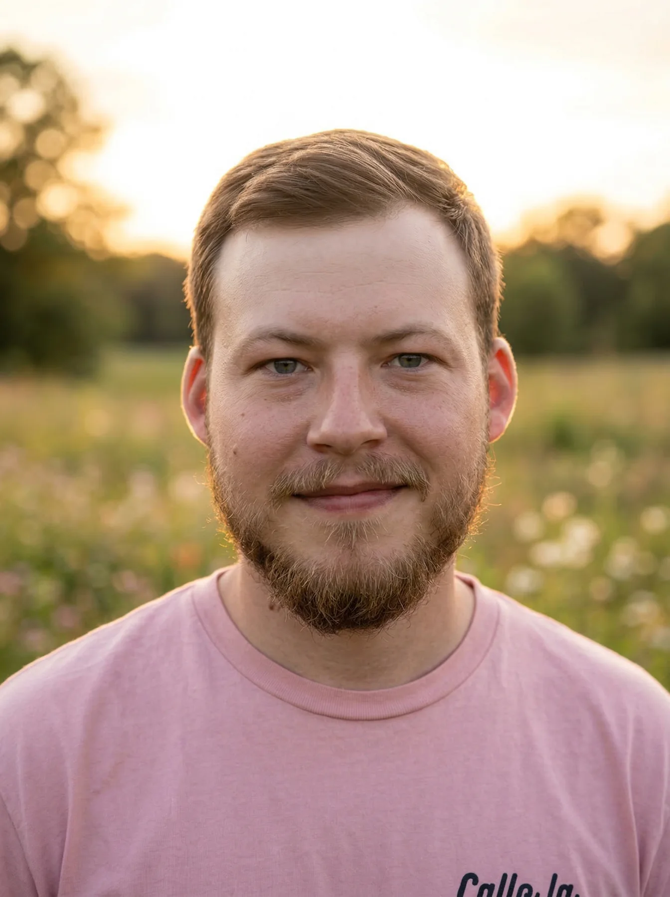 A warm memorial portrait of a man in a softly lit meadow