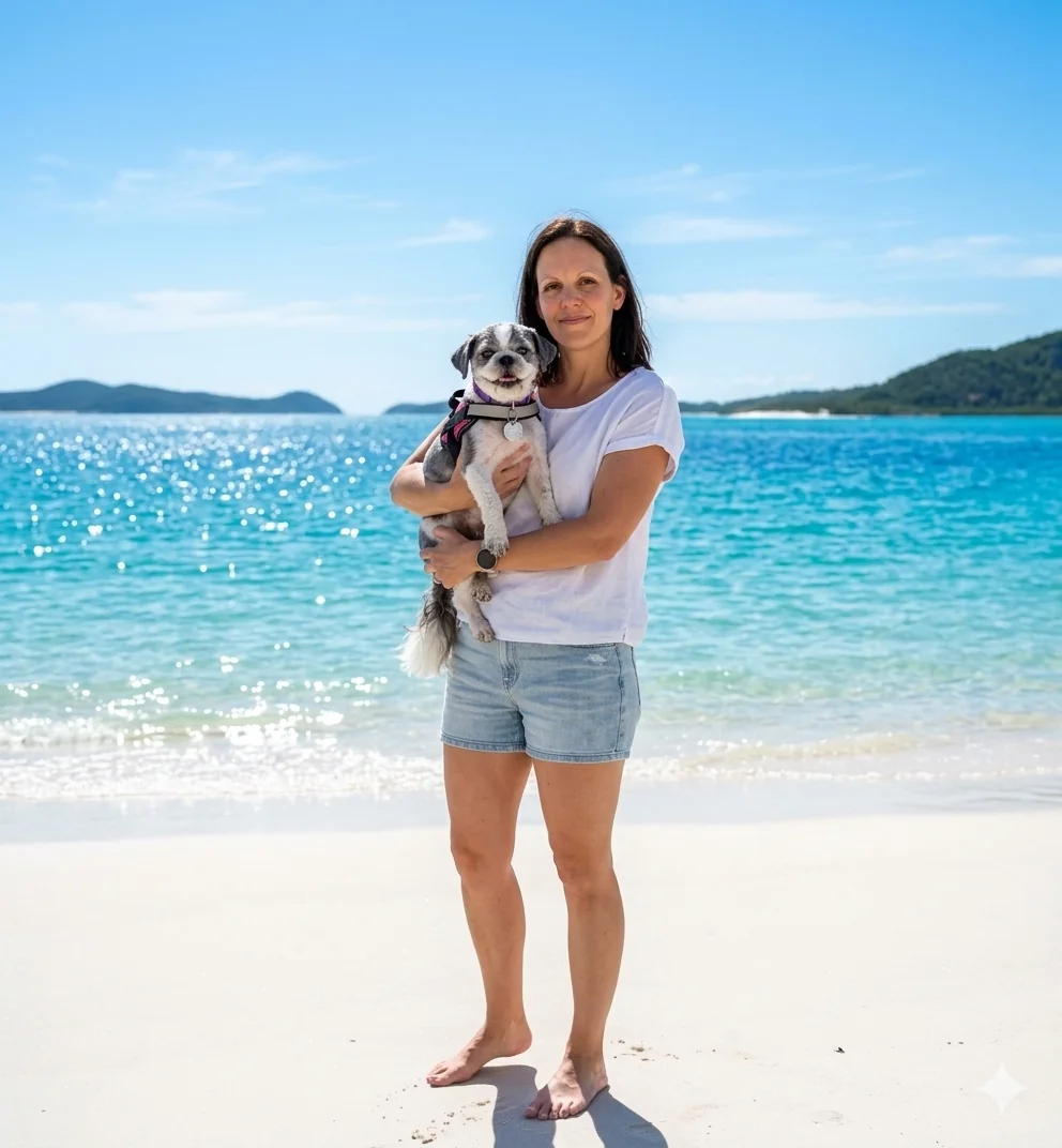 A woman holding her small dog beside bright turquoise water