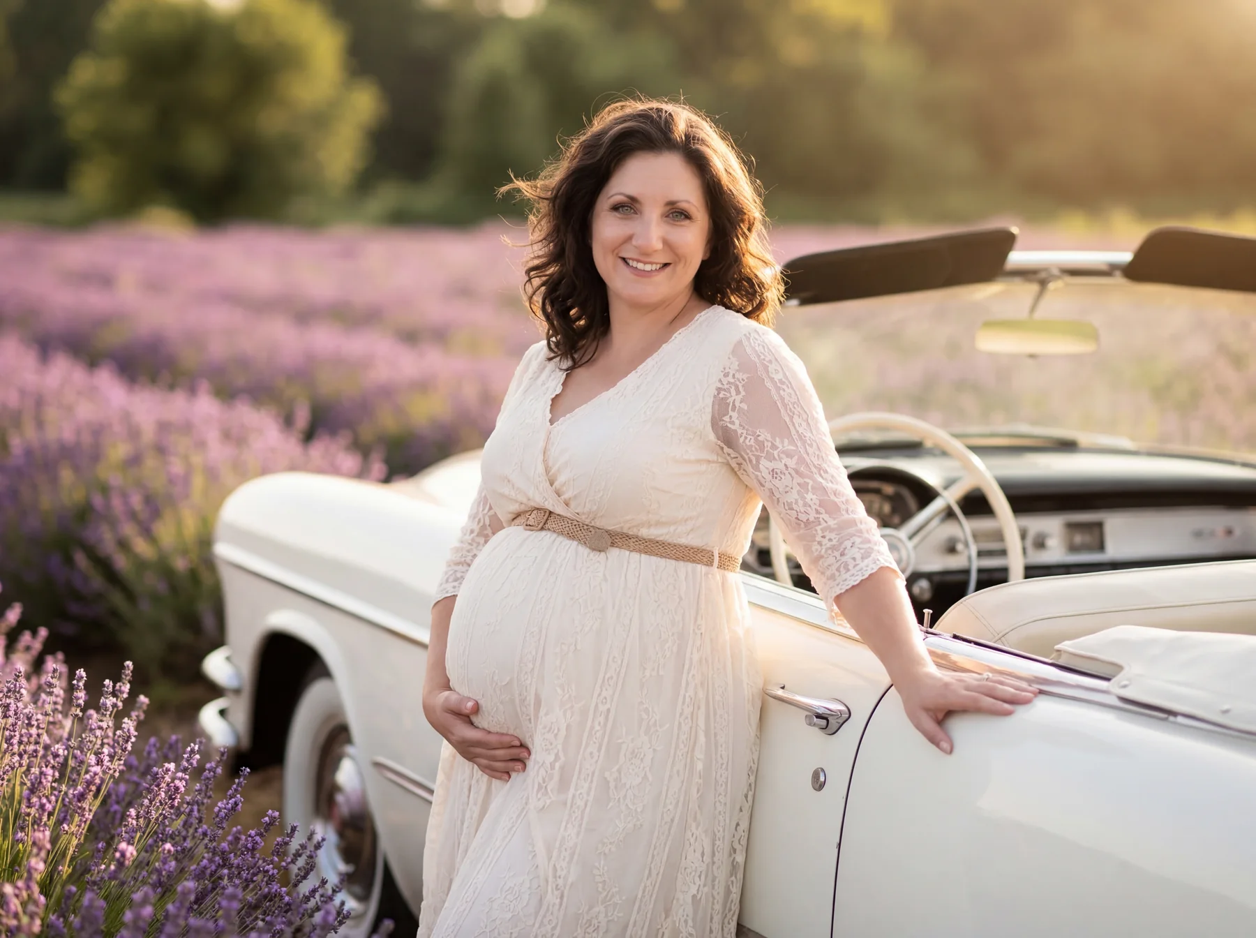 An expectant mother leaning against a vintage car beside lavender fields