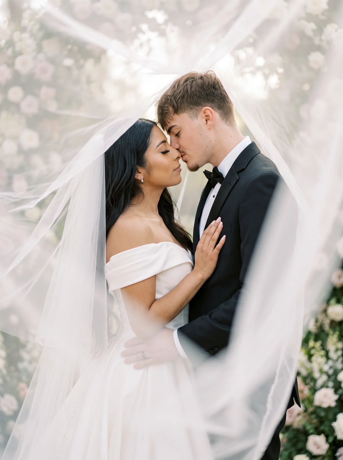 A bride and groom sharing a quiet moment beneath a flowing veil